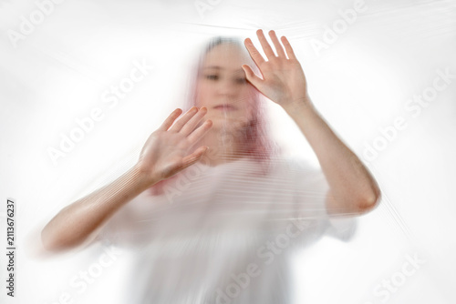 Bild auf Leinwand Woman pressing her hands against transparent plastic, symbolizing eco anxiety, climate change fear, plastic pollution and mental health crisis connected to environmental stress