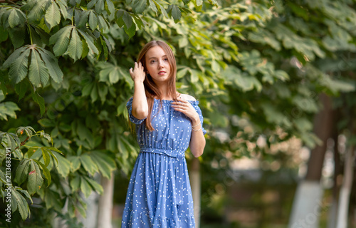 Obraz na plátně A young smiling woman strolls through a spring park in a good mood
