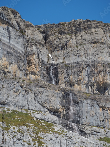 High mountain valley landscape, Ordesa y Monte Perdido National Park, Spanish Pyrenees, with rocky cliffs, forests, blue sky, and clouds.