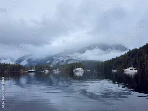 Boats anchored in a tranquil bay with cloud covered mountains