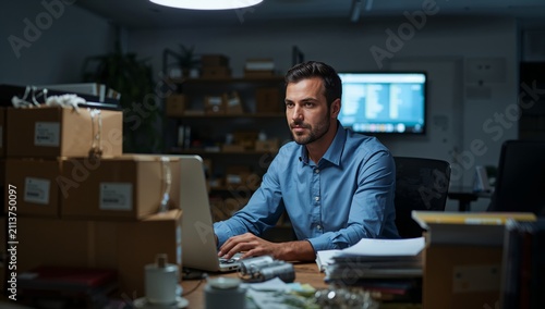 Man Working Late at Night in an Office Filled With Boxes and Files