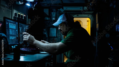Man Working on Computer in Dimly Lit Control Room With Screens