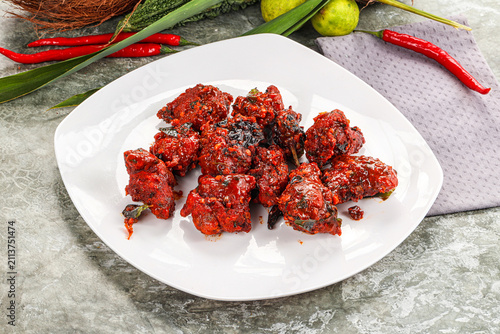 Foto Spicy chicken 65 on white plate with red chilies and lime