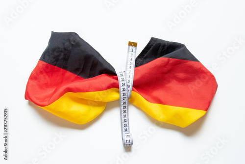 Фотография The German flag and a tape measure on a white background as a symbol of weight c