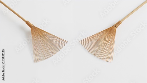 Two Traditional Brooms Made of Natural Materials Placed on a Plain Background