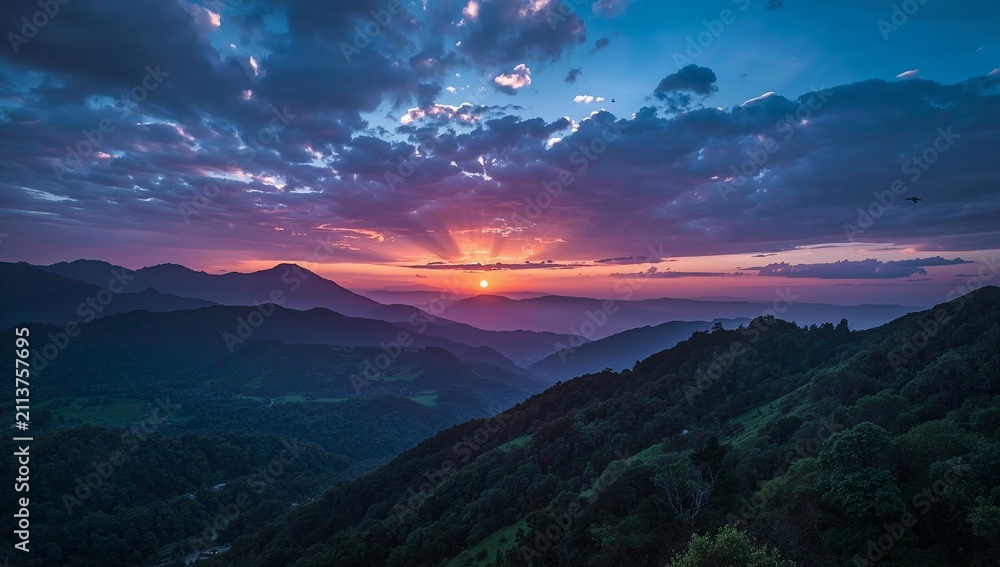 Obraz premium Breathtaking sunset over the rolling mountain ranges with vibrant purple and orange clouds.