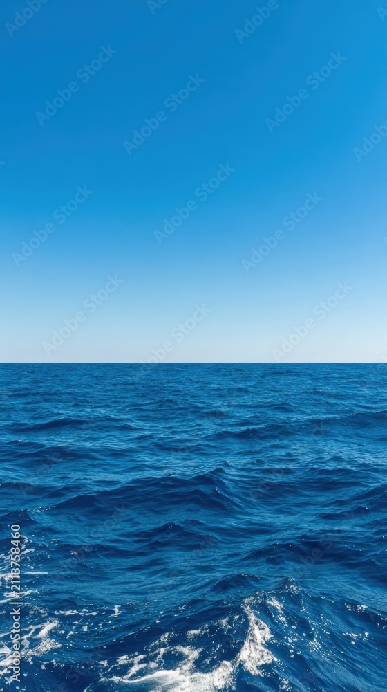 Fototapeta premium Vast ocean under clear blue sky creates a serene atmosphere, perfect for backgrounds or water-themed designs Gentle waves reflect sunlight, providing a tranquil yet dynamic element to any project