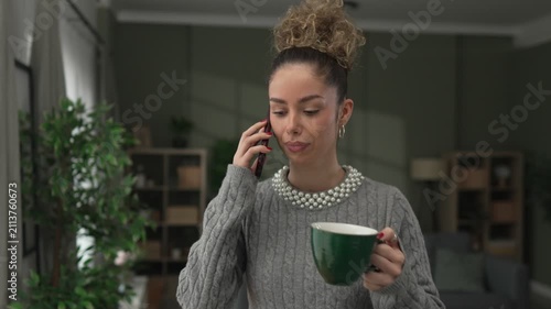 Young woman enjoying coffee and chatting on her smartphone
