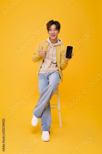 Smartphone mockup with smiling Asian man pointing at blank screen in studio promoting mobile apps digital services online communication advertising and confident technology lifestyle.