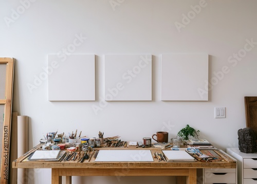 Art studio with empty canvases and various supplies on a wooden table