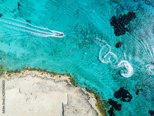 Aerial View of Turquoise Sea and Speedboat Skimming Along Rocky Coastline on Sunny Day, Cyprus, Ayia Napa
