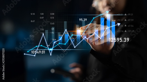Obraz na płótnie A businessman analyzes stock market trends using digital graphs and technology in a dark environment, portraying the importance of data for investment strategies and financial growth