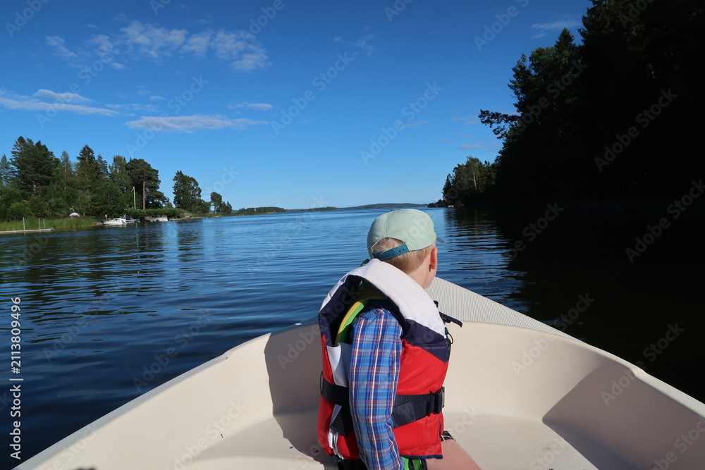 Fototapeta premium 4 Year Old Boy Rowing a Small Boat on Calm Water Near Höllviken, Sweden Summer Adventure