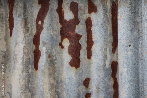 Fotografie The surface of an old corrugated zinc sheet showing severe corrosion or rust on the left side, while the right side still retains its original gray galvanized coating