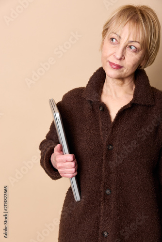 Konstfotografi Senior woman portrait, holding smartphone, gentle smile and sideways gaze, warm