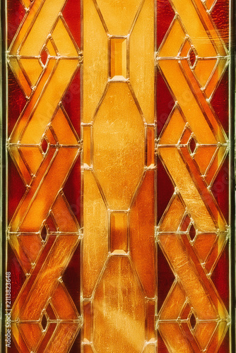 Stained glass window presenting abstract golden red geometric shapes forming a decorative background