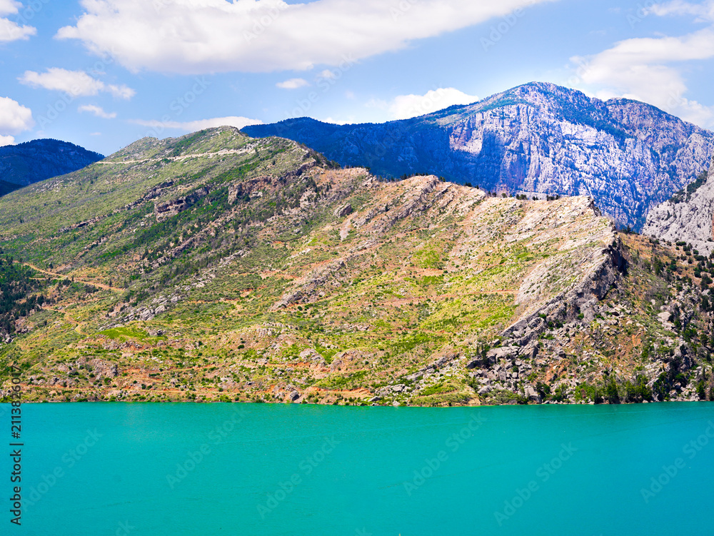 Obraz premium Beautiful scenic view of turquoise water lake and rocky mountains under a blue sky