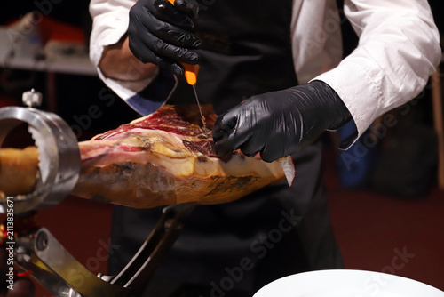 Konstfotografi profesional del corte de jamón ibérico manipulando con guantes un jamón y prepar