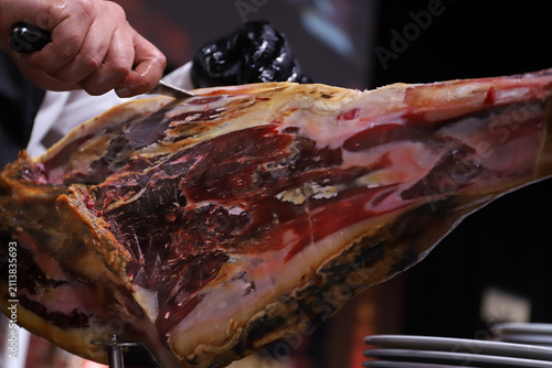 Bild auf Leinwand maestro del corte de jamón limpiando un jamón ibérico de la capa exterior