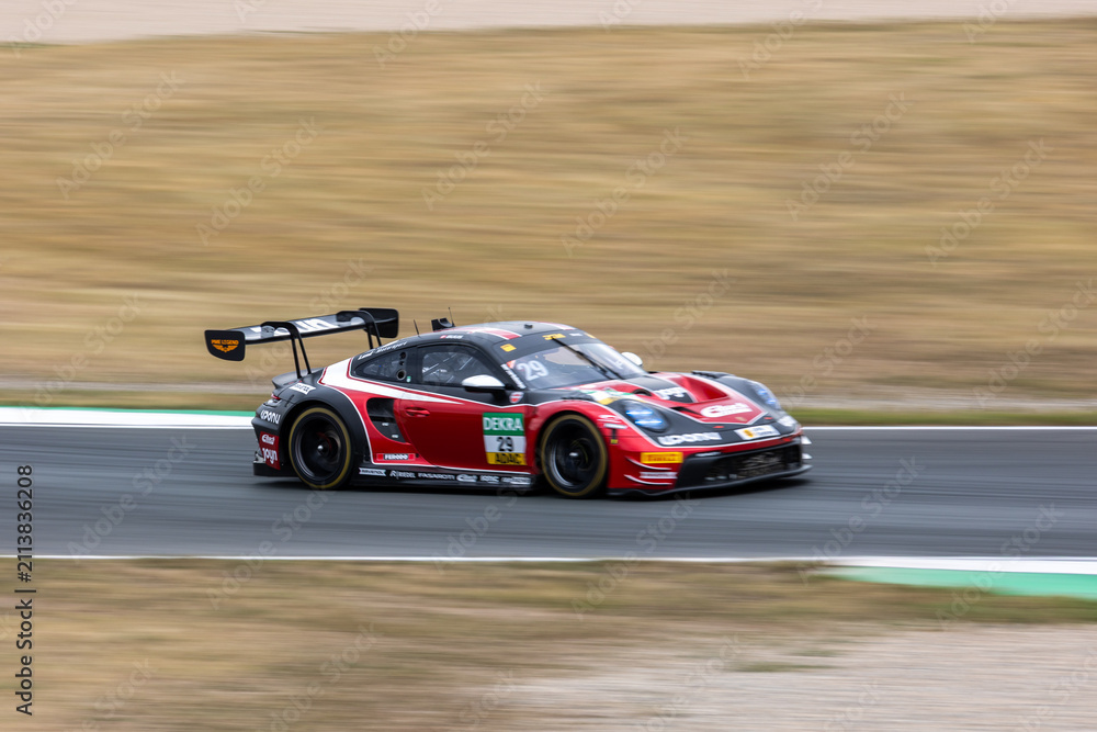 Fototapeta premium Oschersleben, Germany. 26th July 2026. Bastian Buus accelerates through Oschersleben in red, black and white number 29 Land-Motorsport Porsche 911 GT3 R Evo. Smooth panning motion isolates 