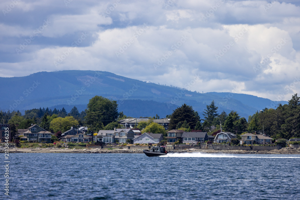 Fototapeta premium Coastal Waterfront Homes With Speedboat Off Sidney, Vancouver Island, BC, Canada and Mountain Clouds