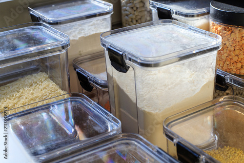 Clear plastic containers filled with flour and grains. Storing dry goods in airtight containers in a well-organized kitchen cabinet drawer