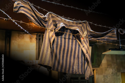 Canvastavla Worn prison uniform hanging on barbed wire fence, fastened with buttons, showing
