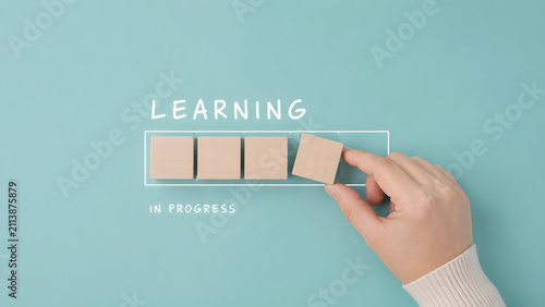 Hand building a learning progress bar with wooden blocks, representing education, skill development, training, continuous improvement, and personal growth.