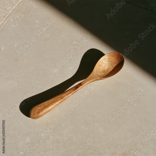 Hand-carved olive wood spoon with worn bowl on stone surface