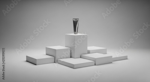 Cosmetic cream tube sits centered upon white tiered display blocks.