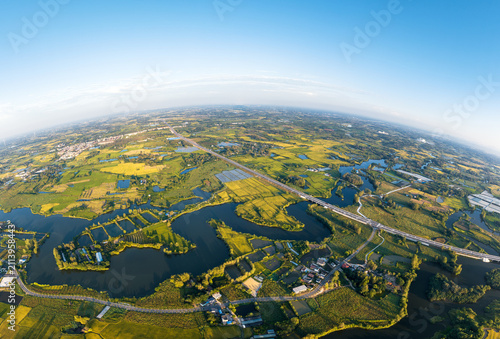 Obraz na płótnie Aerial shot shows a rural landscape with wetlands, farmlands, roads and scattered settlements under clear sky