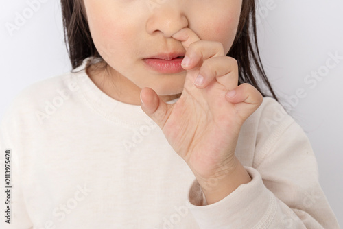 Close-up of a little Chinese girl picking her nose