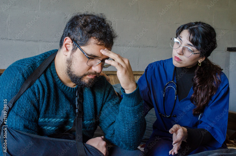 Fototapeta premium Sad injured man with arm sling receiving bad medical news from female doctor