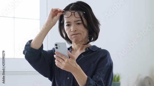 スマートフォンを使う老眼の中高年女性
