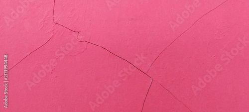 The wall surface is bright pink with fine diagonal cracks.