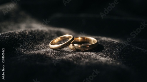 A pair of elegant gold wedding rings resting on a dark, textured surface, symbolizing commitment and eternal love