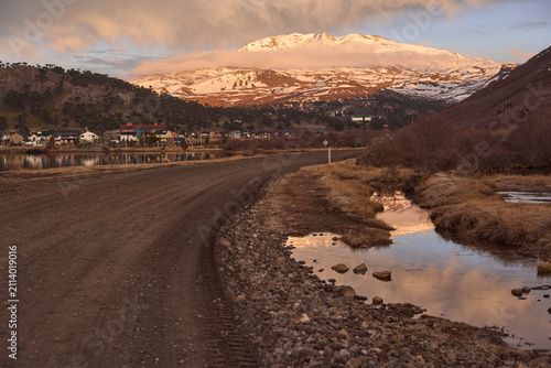 Winter dirt road leading to Caviahue, in Neuquen, Argentina. In the background, the snow-capped Copahue volcano, lighted by the warm morning light.