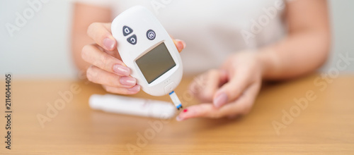 Fotografie Hand checking Diabetes or Blood glucose self testing by digital blood glucose meter with lancet pen