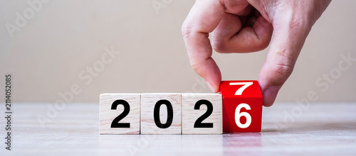 hand flipping block 2026 to 2027 text on table. Resolution, strategy, plan, goal, motivation, reboot, business and New Year holiday concepts