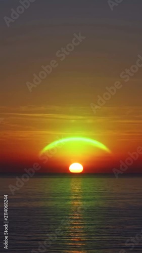Vibrant sunset over the tranquil ocean horizon with a striking green arc phenomenon, creating a breathtaking atmospheric spectacle