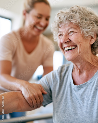Warm light illuminates two women. One smiles brightly, embracing joy. The other offers gentle support. Their connection radiates care. Perfect for wellness or senior care scenes