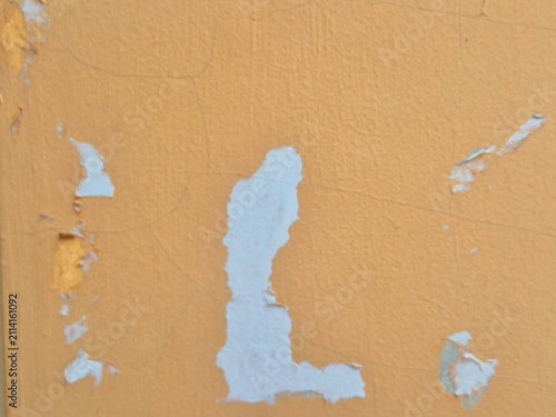 Grungy background texture of chipped orange paint layer on old wall.