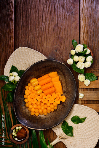 Top View of Traditional Thai Auspicious Sweets Desserts Sweet Golden Egg Yolk Threads Balls Thong Yip Thong Yod and Foi Thong in Ceramic Plate with Jasmine Flower Decoration on Dark Wooden Table