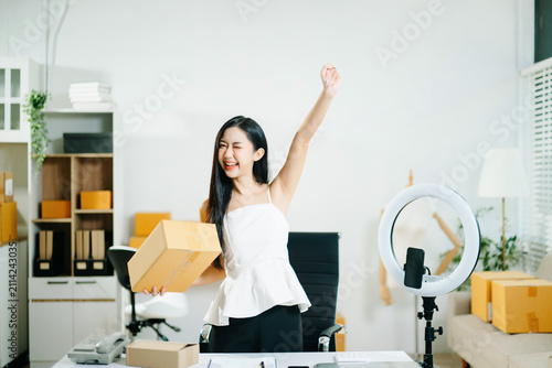 Asian woman livestreaming and packing orders in a home office. ecommerce, online shopping, content creator, influencer, small business