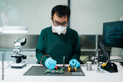 Obraz na płótnie Electronics technician repairing a PCB circuit board using precision tools. Ideal for technology, engineering, hardware maintenance, semiconductor,
