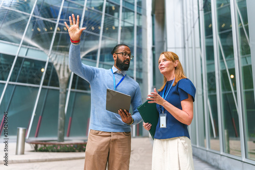Canvas Print Diverse business professionals discussing work outdoors in urban setting with mo