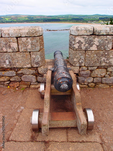 Fotografie Historic iron cannon on wooden carriage on stone castle rampart