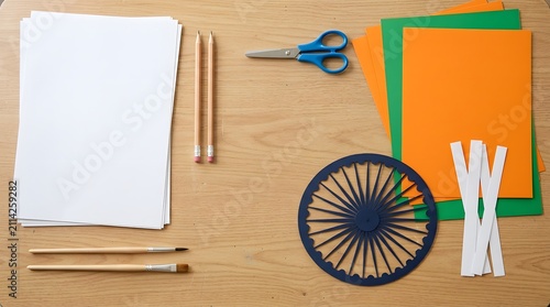Top view of craft materials for india happy independence day celebration with tricolor paper sheets and wooden wheel on table