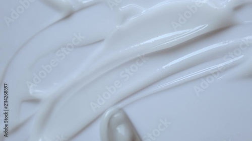 Creamy cosmetic product smearing on white surface for rich texture and skincare concept