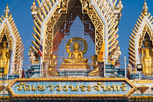 Golden Buddha Shrine: A majestic golden Buddha statue sits at the center of a vibrant shrine, flanked by ornate golden arches and intricate architectural details, under a clear blue sky.